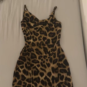 Leopardmönstrad långklänning - Snygg långklänning med leopardmönster och tunna axelband. Klänningen har en figurnära passform upptill och faller snyggt längs kroppen. Perfekt för dig som vill sticka ut med ett djurmönster i bruna och svarta toner.från pretty little things