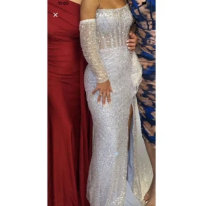 Glittrig silver balklänning med slits - Superfin långklänning i silver med glittriga paljetter över hela klänningen. Storlek 34, köpt från Södertälje. Nypris 7000kr 