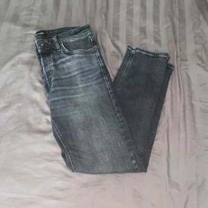 Grå tapered jeans från Jack & Jones - Snygga grå jeans från Jack & Jones i modellen Tapered Mike. Jeansen har en tvättad look med ljusare partier och klassiska fem fickor. Jeansen är i bra skick använder inte dem. 