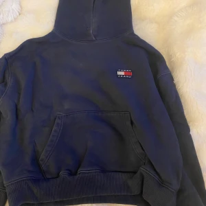 Mörkblå hoodie från Tommy Jeans XS - Mörkblå hoodie från Tommy Jeans i storlek XS. Klassisk modell med huva, magficka och broderad logga på bröstet. Mjuk och skön bomullsblandning, perfekt för chill dagar. Snygg ribbad mudd vid ärmslut och nederkant.