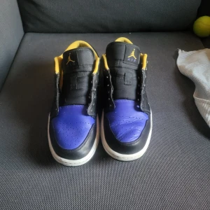 Nike Air Jordan 1 Low svart/blå/gul - Säljer ett par Nike Air Jordan 1 Low med svart och blå ovandel i skinn, gula detaljer på insidan. Andvände dem som gym/basket skor därför dem är lite creased men jätte bra skick annars inga hål/märken på dem. (KAN ÄVEN BYTAS MOT SKOR, KLÄDER)