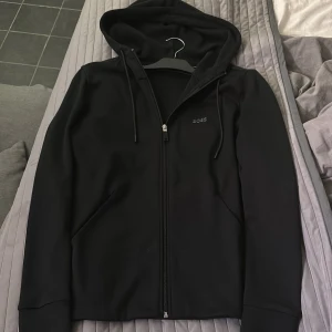 Svart hoodie från BOSS med dragkedja - Tjena säljer min Hugo boss zip i färgen svart som är storlek s passar även xs väldigt skön med skönt sport material, köpt för 1300 mitt pris 700 pris kan diskutera. Använd 2-4 gånger verkligen inget fel på den bra skick hör av er vid intresse🙌🏼