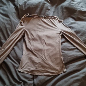 Grå långärmad topp med slits - Säljer en grå långärmad topp från Bikbok med slitsdetaljer vid ärmsluten. Toppen har en enkel, tight passform och är tillverkad i mjuk bomullsmix. Perfekt för dig som gillar stilrena basics med en twist. Lite trasig i slutet av ärmen men det är inget som märks.