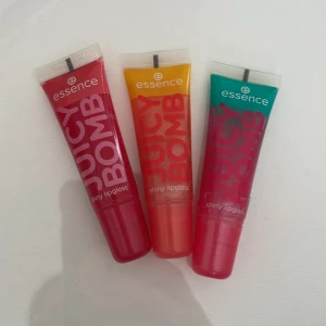 Essence Juicy Bomb Lipgloss 3-pack - Tre tuber Essence Juicy Bomb shiny lipgloss i färgerna röd (Poppin' Pomegranate), orange (Proud Papaya) och turkos/rosa (Witty Watermelon). Glansen är vegansk, har fruktiga dofter och kommer i mjuka plasttuber med skruvkork. Perfekt för dig som gillar gloss med färg och glans. 2 stycken är testade en gång men avtorkade efter!