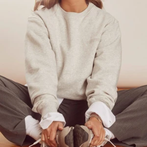 Grå sweatshirt från Djerf Avenue - Säljer en ljusgrå sweatshirt från Djerf Avenue med broderad logga på bröstet. Tröjan har rund hals, ribbade muddar och långärmad passform. Den är skrynklig på bilderna, men det är bara att stryka💋nypris 1200 kr