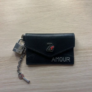 Svart Zadig & Voltaire plånbok med lås - Cool svart plånbok i skinn från Zadig & Voltaire med silverfärgat lås och kedja.  Rymlig och skit cool! Endast använd några gånger och i toppenskick🫰🏽 nypris ligger på ca 2000