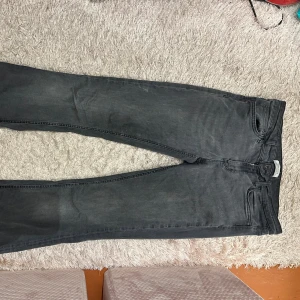 Mörkgrå jeans från Zara Woman - Snygga mörkgrå jeans från Zara Woman med bootcut. Jeansen har dragkedja och knapp framtill, samt bälteshällor. Materialet är mjukt och stretchigt jeans, vilket gör dem bekväma att bära hela dagen.
