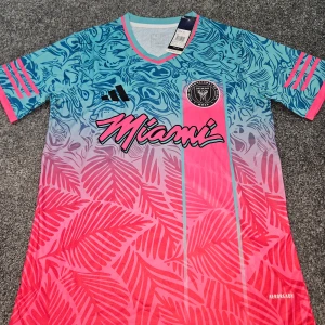 Inter Miami fotbollströja Adidas S - Snygg Inter Miami fotbollströja från Adidas med färgstark design i blått och rosa, palmmönster och coola detaljer. Tröjan har korta ärmar, V-ringning och är tillverkad i lätt AEROREADY-material som andas. Perfekt för dig som vill sticka ut på planen eller läktaren.