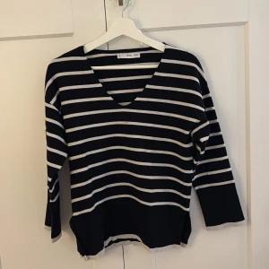 Randig svartvit tröja från MANGO - Svart och vit randig tröja från MANGO med v-ringning och lång ärm. Tröjan har en loose passform och är stickad i mjukt material, perfekt för lager på lager. Snygg till både jeans och kjol.