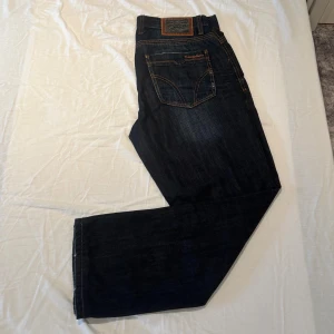 Jeans från Dolce & Gabbana - Snygga mörkblå jeans från Dolce & Gabbana. Jeansen har rak passform och tydlig logotyp på bakfickan samt läderpatch i midjan. Skicket är som nya. Storlek 34/34.