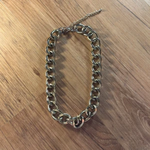 Chunky guldfärgat halsband från H&M - Stilrent chunky halsband i guldfärg med stora, ovala länkar och justerbar kedja. Perfekt statement piece för dig som vill sticka ut och ge din outfit en cool edge. Metallfinishen ger ett lyxigt intryck och passar till många olika stilar.