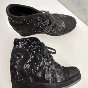 Sneakers m paljetter och klack - Ett par snygga svarta sneakers (med klack inuti) från italienska Rucoline. Skorna har en kilklack och är dekorerade med paljetter. Material är bland annat skinn. Köpta för 2400 kr  Mycket fint använt skick. Syns typ bara på sulan att de är använda. Storlek 40.