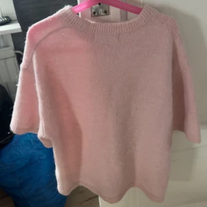 Ljusrosa stickad tröja - Supermysig ljusrosa stickad tröja med kortare ärmar och rund hals. Perfekt att slänga på sig när det är lite kyligt ute. Enkel och stilren design som passar till det mesta.