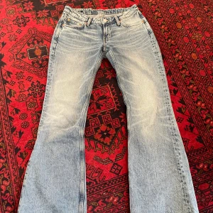 Low waist bootcut jeans från Weekday - Ett par ljusblå lågmidjade flare jeans från weekday. Säljer eftersom de ej kommer till användning. Jag köpte dem i somras och de har blivit använda ca 2 gånger. Skicket är så gott som nytt! Materialet är 100% bomull                                                                                          Nypris: 600kr                                                                                Midjemått(tvärs över): 40cm                                                Innerbenslängd: 82cm