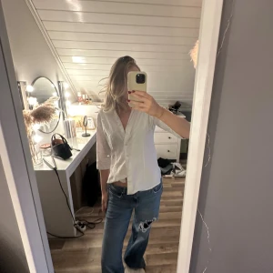 Vit skjorta med trekvartsärm - Säljer en stilren vit skjorta med trekvartsärm och klassisk krage. Skjortan har knappar framtill och är gjord i ett lätt bomullstyg som känns fräscht och luftigt. Perfekt för dig som gillar en clean och enkel look.