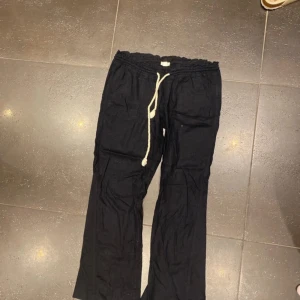 Roxy linnebyxor  - Marinblå linnebyxor med avslappnad passform och vit snörning i midjan. Byxorna har raka ben och resår i midjan för extra komfort. Perfekta för en chill och stilren look.