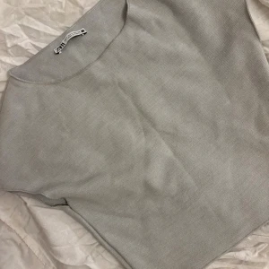Ljusgrå stickad tröja från Zara - Säljer en stilren ljusgrå stickad tröja från Zara i storlek S. Tröjan har en enkel design med rund hals och är tillverkad i mjukt stickat material som känns skönt mot huden. Perfekt för lager-på-lager och passar till många olika looks.