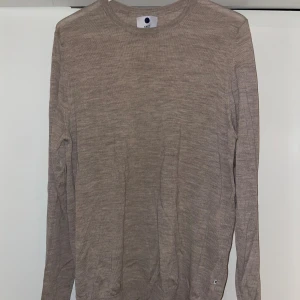 Beige stickad ”Charles” tröja från NN07 - Säljer en sjukt snygg beige tunn stickad tröja från NN07. Tröjan har rund halsringning och långa ärmar, perfekt för lager-på-lager. Mjuk och tunn i materialet, passar grymt till både jeans och chinos.