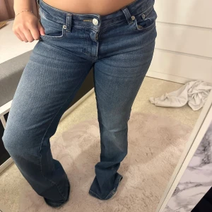 Blå low bootcut jeans - Snygga blåa  jeans med bootcut och låg midja. Klassisk femficksmodell med silverfärgade nitar och knappar. Jeansen har en rak passform över låren och lite utsvängda ben. Obs byxorna har minimalt slitage längst ner