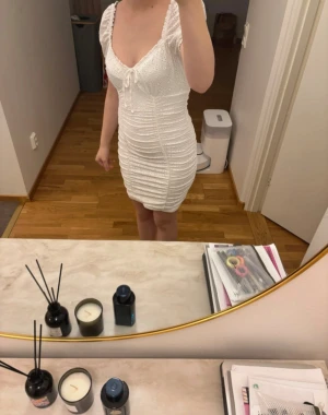 Vit kort klänning med puffärm - Supersöt vit kort klänning med puffärmar och broderade detaljer. Klänningen har v-ringad hals med snörning framtill och är rynkad längs hela kroppen för en tight och smickrande passform. Perfekt för sommarens alla tillfällen! Knappt använd förutom 1 gång säljs nu då den inte används något mer.