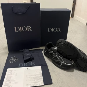 Dior B30 svarta sneakers - Säljer ett par svarta Dior B30 sneakers med coola reflekterande detaljer och tydlig Dior-logga på sidan. Skorna har en chunky sula, snörning och är tillverkade i en mix av mesh och syntetmaterial för en sportig vibe. Kommer med originalförpackning, dustbag och tillbehör. Äkta med kvitto på mejl. Byten funkar, 