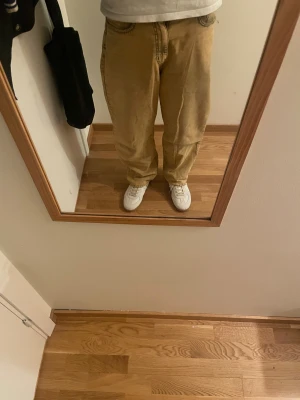 Beige wide jeans med rå kant - Säljer ett par beige jeans med bred passform och rå, fransig kant längst ner. Byxorna har klassisk femficksdesign och är tillverkade i jeansmaterial. Perfekt för dig som gillar en avslappnad och trendig stil.