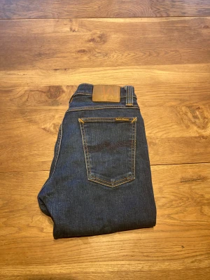Nudie Jeans, Tube Kelly, W29 L32 - Snygga mörkblå jeans från Nudie Jeans med klassisk ficksdesign. Modellen har rak passform och normal midja.  Jeansen har storleken W29, L32.