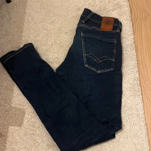 Replay Anbass mörkblå jeans - Snygga mörkblå Replay Anbass jeans med klassisk femficksdesign och kontrastsömmar. Jeansen har en rak passform och är tillverkade i slitstarkt denim med coola detaljer på bakfickorna och Replay-logga på myntfickan.