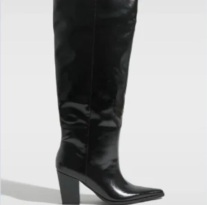 Svarta höga stövlar med klack - Säljer ett par svarta, glansiga stövlar med spetsig tå. Har endast använt de en gång inomhus! Nypris: 799 kr