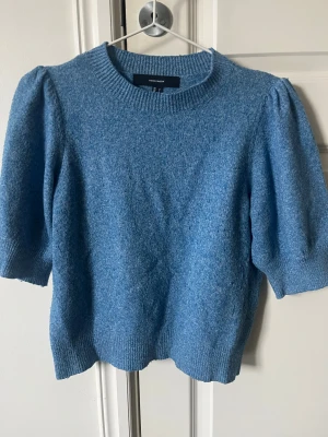 Blå stickad tröja Vero Moda  - Mysig blå stickad tröja från Vero Moda i storlek S. Tröjan har puffade korta ärmar och ribbad rund halsringning samt ribbade muddar. Perfekt för dig som gillar en enkel men ändå trendig look med lite volym på axlarna.