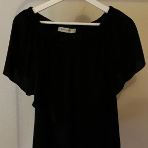 Svart offshoulder kortklänning - Svart kortklänning från Bik Bok med offshoulder-modell och vida, fladdriga ärmar. Klänningen har en lös passform 