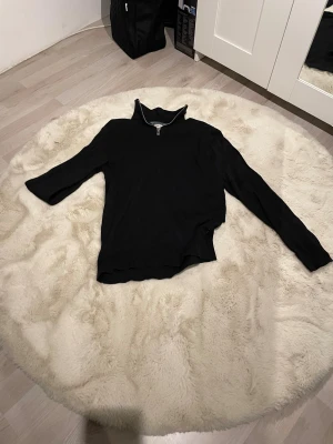 Svart quarter zip stickad tröja Jack & Jones - Svart stickad tröja från Jack & Jones i storlek XS. Tröjan har en hög krage med half zip-dragkedja och långa ärmar. Materialet är en mjuk blandning av bomull och polyester, perfekt för dig som gillar stilren och enkel design.