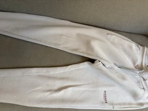 Beige mjukisbyxor från McKenzie - Snygga beige mjukisbyxor från McKenzie med ribbad midja och snörning. Byxorna har en slim passform och är tillverkade i mjukt bomullsmaterial. Diskret logga på benet och praktiska fickor. Perfekta för chill eller träning.