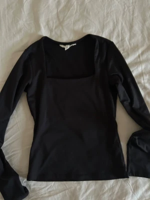 Svart långärmad topp med fyrkantig ringning - Säljer en svart långärmad topp från H&M i storlek XS. Toppen har en snygg fyrkantig ringning och är figurnära i modellen