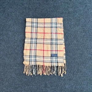 Burberry scarf - Burberry-scarf som är 100% äkta. Mindre defekter kan förekomma enligt bild men inget märkvärdigt då de är vintage. Snabb leverans och trygg handel då vi har 7 års erfarenhet i branschen. Vid frågor eller bud, skicka gärna ett meddelande. 1008