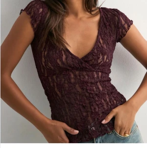 Vinröd spetsblus från Nelly - Säljer en vinröd spetsblus från Nelly med omlott och djup v-ringning. Blusen är genombruten med korta ärmar och har en snygg croppad passform. Perfekt för dig som vill sticka ut med en romantisk och trendig look.