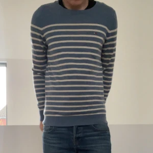 Ljusblå Tommy hilfiger stickad randig tröja  - Säljer en sjukt fet tröja från Tommy hilfiger som är randigt stickad i färgen ljusblå och vit. Detta mönstret är upcoming och blir mer och mer populärt hela tiden. Tröjan är i ull och hör gärna av er vid frågor elr funderingar!!