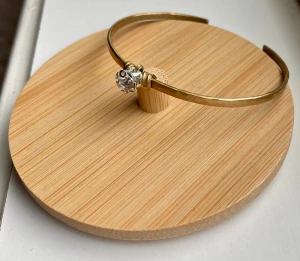 Guldfärgat armband med kristall - Stilrent guldfärgat armband med en gnistrande klar kristall i mitten. Armbandet har en öppen design och en lätt hamrad yta som ger en cool touch. Perfekt för dig som gillar minimalistiska smycken med lite extra bling. Mässing 