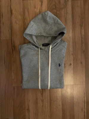 Grå hoodie från Polo Ralph Lauren - ny med taggar. Mjuk, bekväm och passar perfekt till vardags eller chill. Diskret broderad logga på bröstet.    💰 Pris: 649kr  📦 Fraktas snabbt Den kan passa M, beror på hur mycket man väger, och hur lång man är