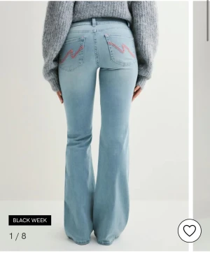 såljer dessa jeans, använda en gång, i storlek 34 - Snygga ljusblå jeans med bootcut-modell och broderade detaljer i rosa på bakfickorna. Jeansen har hög midja och är tillverkade i klassiskt denimtyg. Perfekta för dig som gillar en retroinspirerad look med extra attityd. 
