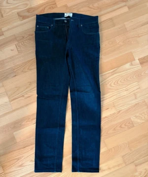 Mörkblå jeans Acne Studios Ace Rossi - Snygga mörkblå jeans från Acne Studios, modell Ace Rossi. Klassisk femficksdesign med raka ben och normal passform. Tillverkade i stretchig denim av 97% bomull och 3% elastan för skön komfort. Perfekta för dig som gillar stilrena och tidlösa jeans.