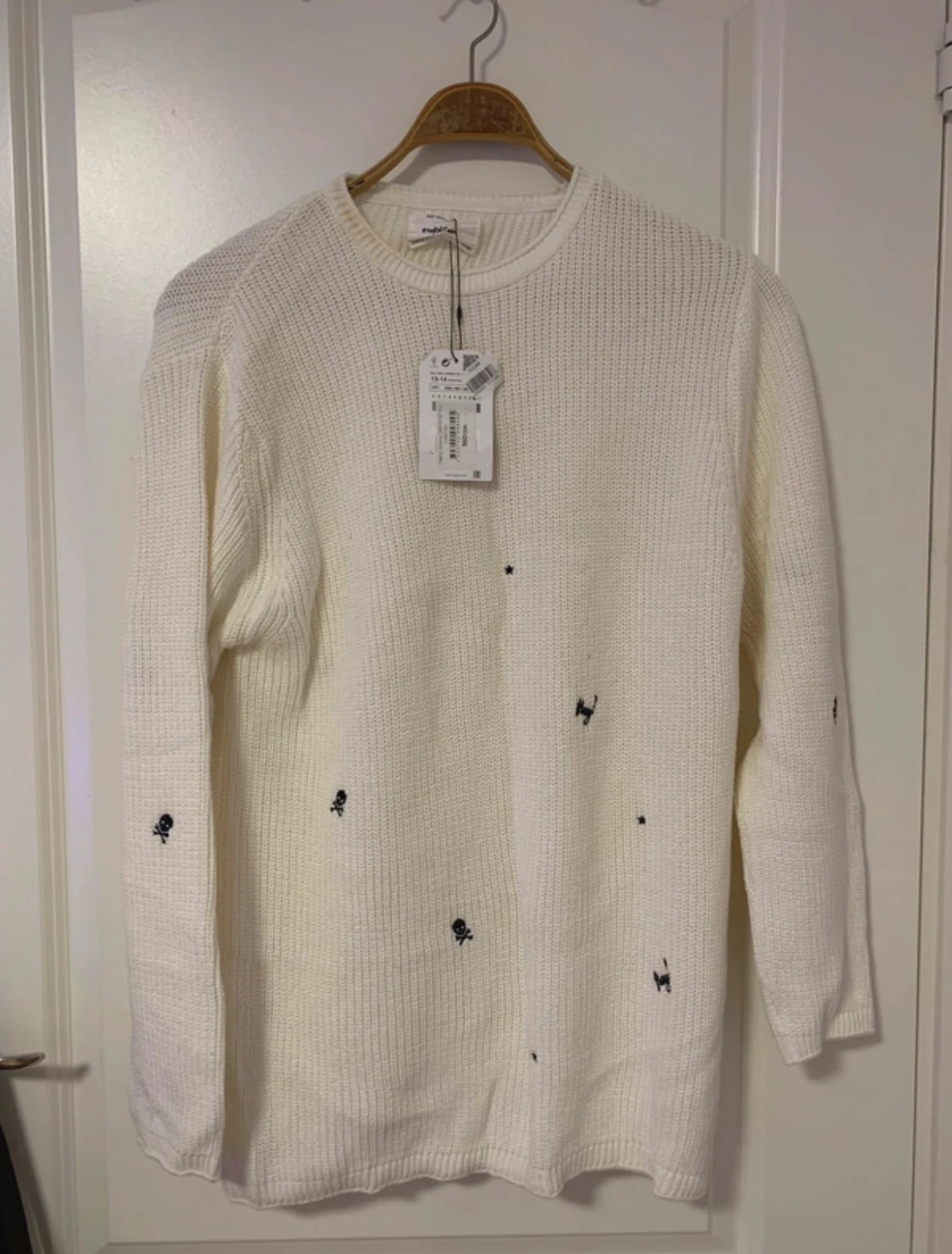 Vit stickad tröja med svarta symboler