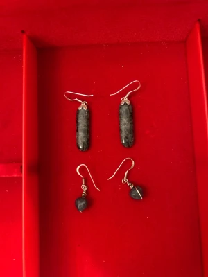Två par äkta silver örhängen med grå sten - Säljer två par snygga äkta silver örhängen med gråmelerad sten. Ett par har avlånga, cylinderformade stenar och det andra har droppformade stenar. Båda har silverfärgade krokar och detaljer. Perfekt för dig som gillar unika accessoarer med naturlig vibe.