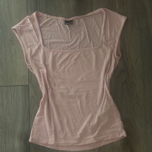 Ljusrosa topp från gina tricot - Säljer en ljusrosa topp från Gina Tricot i storlek S/XS. Toppen har en snygg fyrkantig halsringning och är ärmlös med en slim passform. Materialet är mjukt och stretchigt, perfekt för att styla med jeans eller kjol. Enkel och fräsch design som är lätt att matcha.