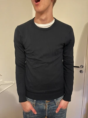 Mörkblå stickad tröja från Bläck - En stilren svart stickad tröja från Bläck i storlek S. Tröjan har rund halsringning, ribbade muddar och är långärmad. Enkel och clean design som passar till det mesta. Skriv vid minsta fråga!!!