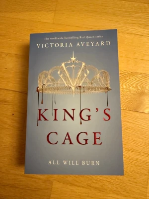 King's Cage by Victoria Aveyard English - King's Cage är en spännande del av Red Queen-serien där makt, svek och kärlek står i centrum. Följ Mare Barrow som kämpar mot sina fiender och sin egen fångenskap, medan rebellernas öde avgörs. Perfekt för dig som gillar fantasy, drama och episka konflikter!