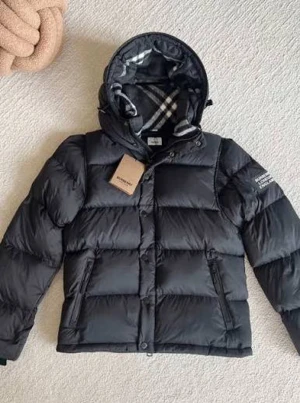 Svart pufferjacka från Burberry XL - Svart pufferjacka från Burberry med huva och klassiskt grått rutigt foder. Jackan har dragkedja och knappar framtill, samt två sidofickor med dragkedja. Perfekt för kalla dagar och har en modern, boxig passform. Jackan kan bli till en väst. Den är Xl men passar som L och den är helt ny. 2300 men priset kan diskuteras.
