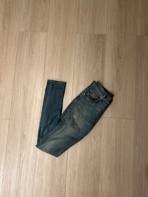 Tiger of Sweden blå jeans skinny fit - Snygga blå jeans från Tiger of Sweden med skinny fit och klassisk femficksdesign. Jeansen har gul kontrastsöm, knappstängning och läderpatch med logga bak. Materialet är slitstarkt denim i bomull. Perfekt för dig som gillar en smal siluett och stilren look. Om det är så att ni har frågor är det bara att ge mig en signal svarar oftast inom 2 timmar och skickar samma dag om man beställer innan 19:00