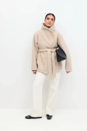 Beige teddyjacka med bälte Gina Tricot - Säljer en beige teddyjacka från Gina Tricot i storlek M. Jackan har bred krage, knytbälte i midjan och långärmade ärmar. Materialet är mjukt och fluffigt, perfekt för kyliga dagar. Enkel och stilren design som ger en chill vibe.