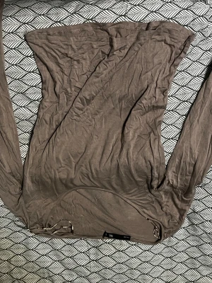 Brun långärmad tubtopp från Bik Bok - Säljer en brun tubtopp från Bik Bok i storlek S. Toppen är axelbandslös med långa ärmar och har en tight passform. Materialet är mjukt och stretchigt, perfekt för dig som gillar minimalistisk stil och vill ha något som sitter snyggt.